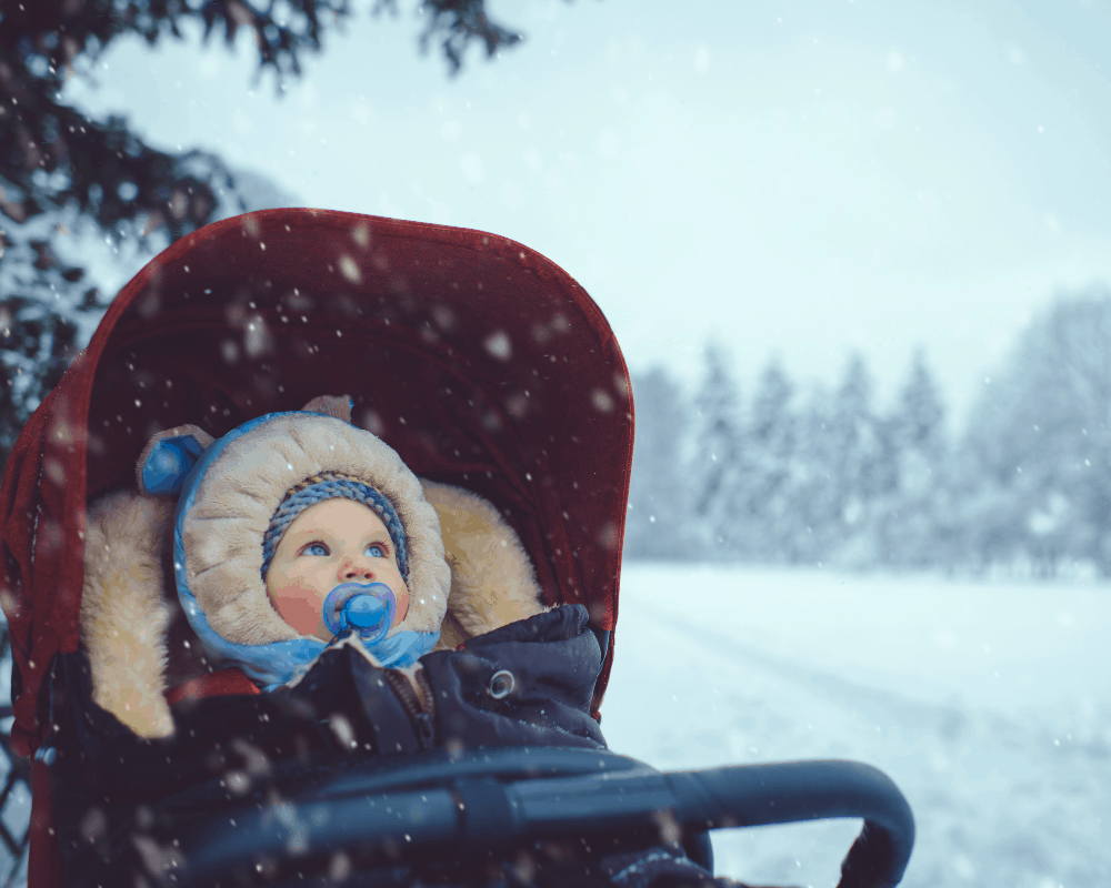 Babyen er i vognposen i vognen utendørs om vinteren.
