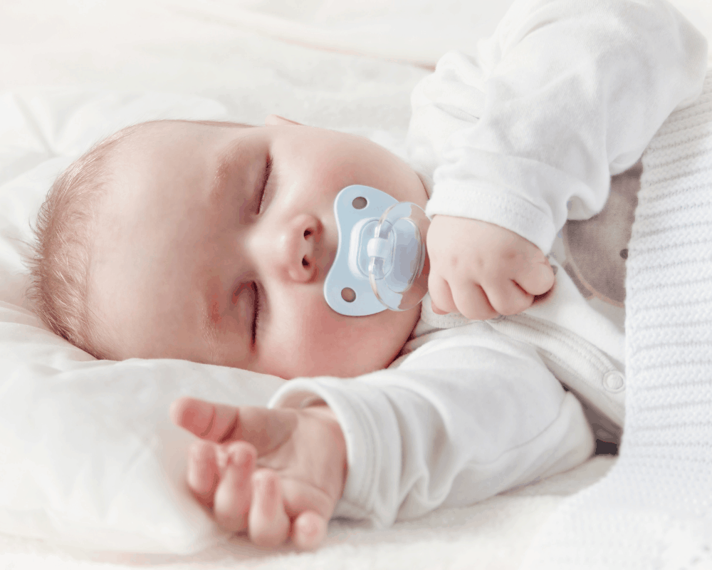 Baby sover med blå smokk i munnen