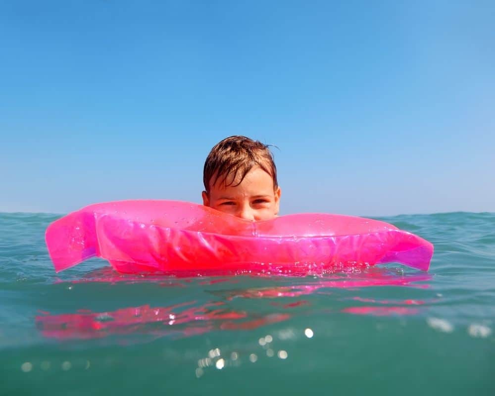 Barn med rosa flytemadrass i vannet
