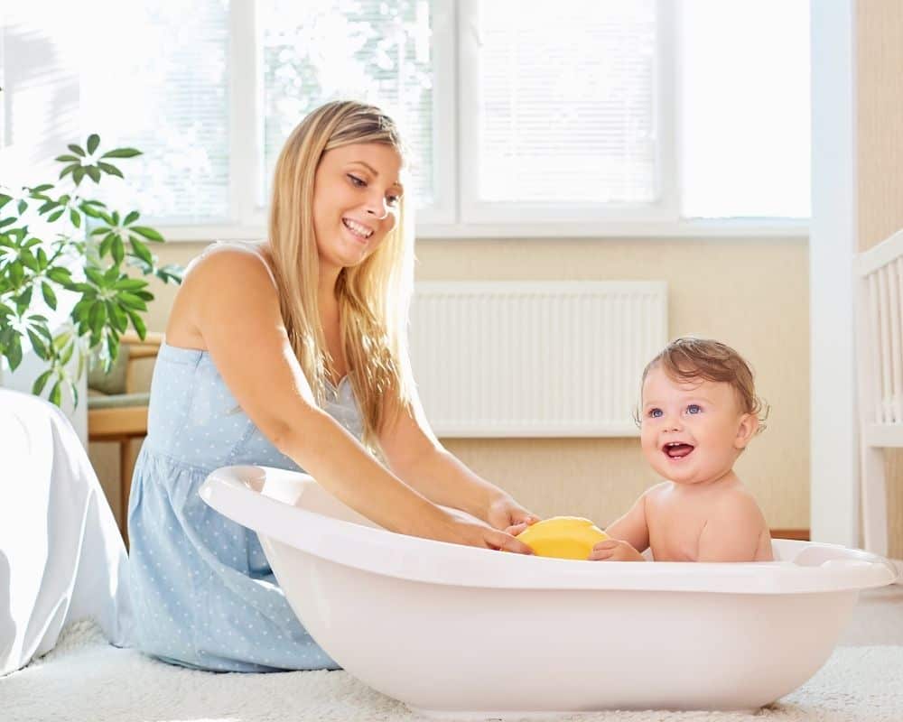 Glad mor bader barnet sitt i en badebalje