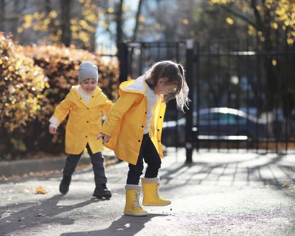 To barn i gule høstklær som leker utendørs