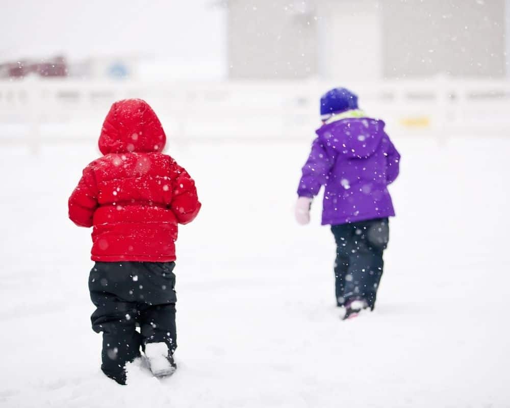 To barn går i snøvær om vinteren