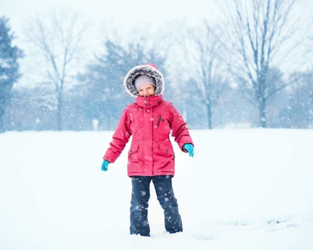 Barn utendørs i snøen med vinterjakke på