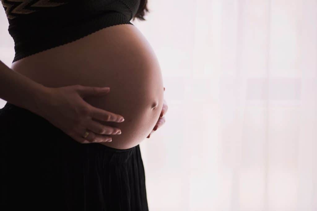Nærbilde av gravidmage, svart topp og svart gravidtights